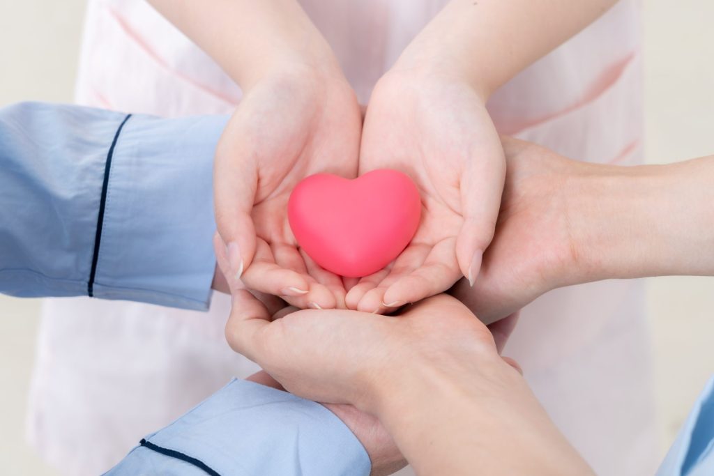ハートを患者、看護師、医師が掌で支えあっている画像